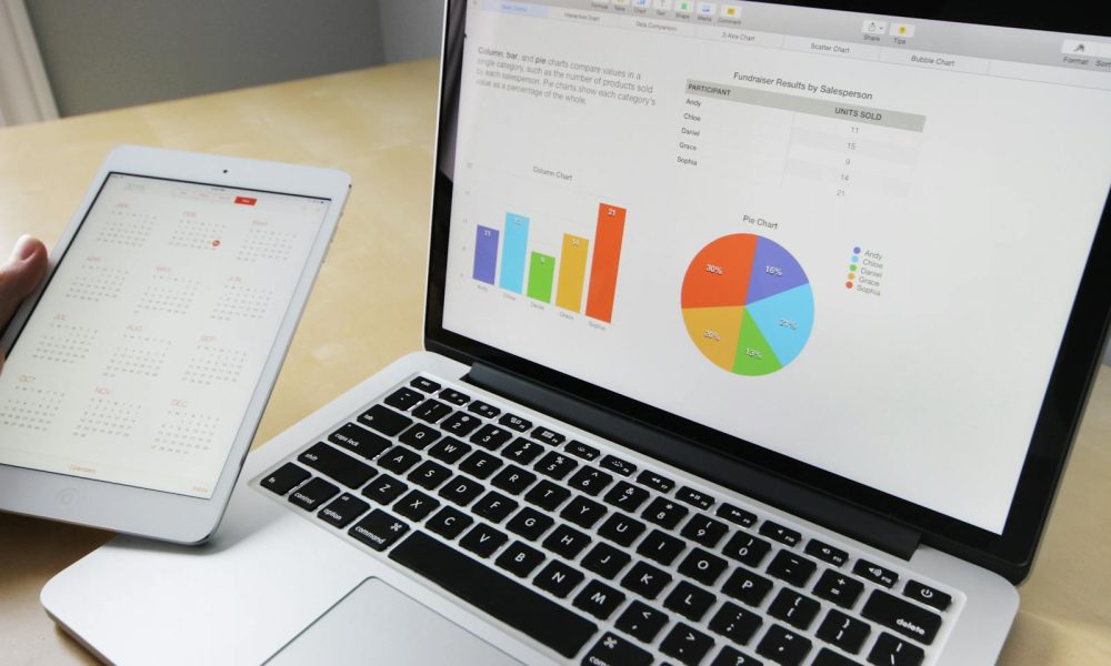 Laptop displaying charts and graphs with tablet calendar for data analysis and planning.