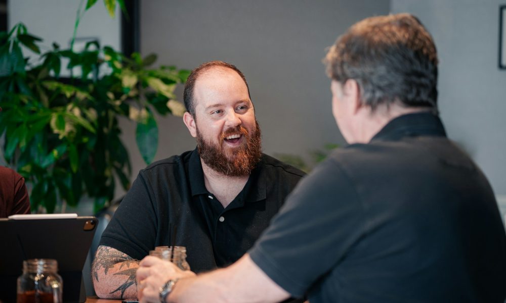 two men sitting at a table talking to each other