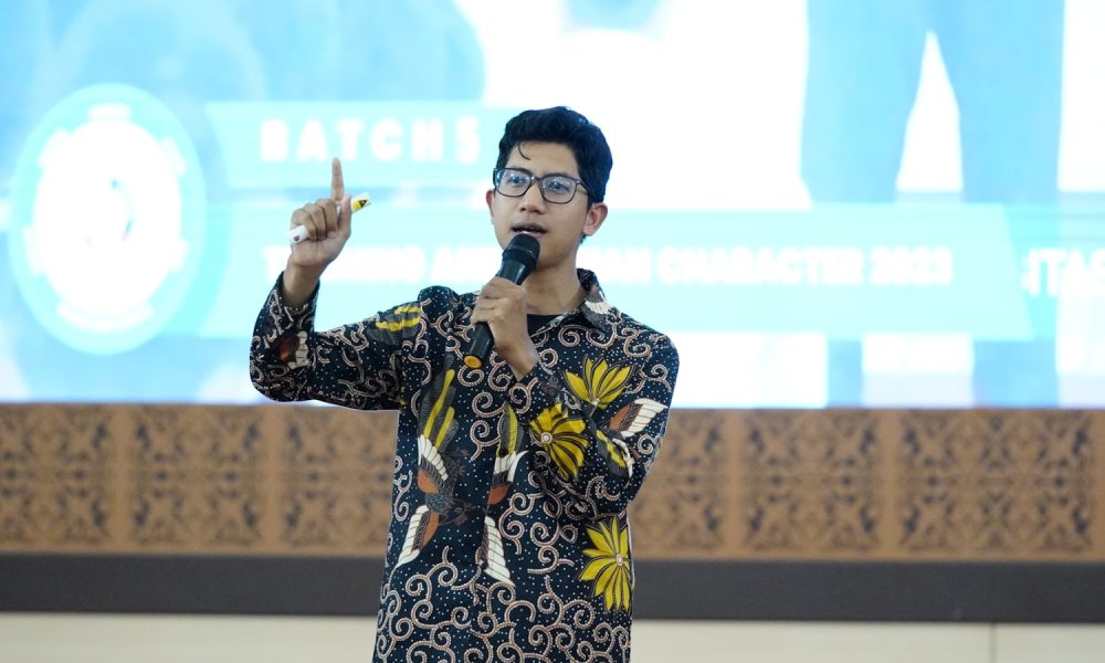 a man standing in front of a screen holding a microphone