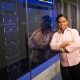Black woman engineer with crossed arms standing in a server room, smiling confidently.